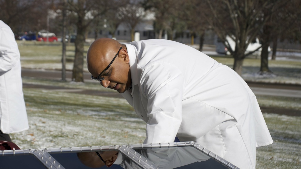 Man stands in front of solar panel in Coralville Iowa